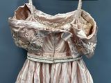 a pink dress hanging on a hanger on a blue wall
