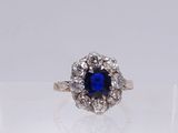 a close up of a blue sapphire and diamond ring on a clear surface