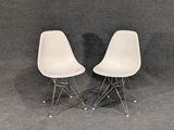 pair of white plastic chairs with chrome legs against a gray background