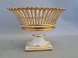 a white and gold bowl on a stand on a table