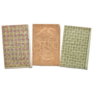 three small notebooks are lined up on a white surface