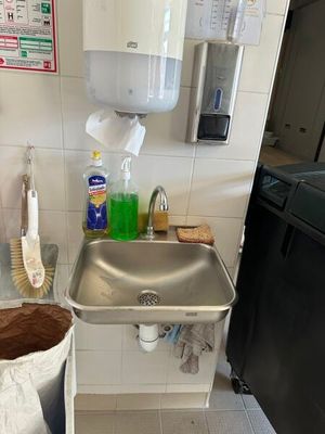 un évier dans un coin de la cuisine, avec une poubelle