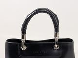 black leather handbag with bamboo handles on a white background
