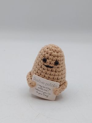 une petite peluche tenant une pancarte sur une surface blanche