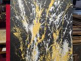de la peinture jaune et noire éclaboussée sur une toile posée sur un chevalet en bois