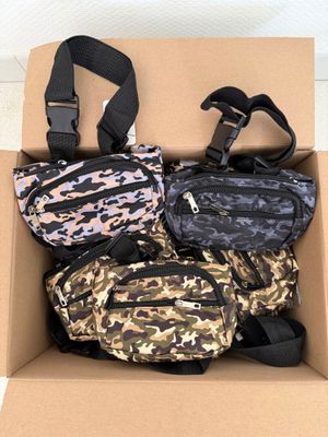 three fanny bags in a cardboard box on a white floor