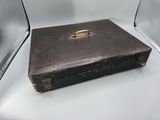 an old black suitcase sitting on a white table