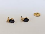 une paire de boucles d'oreilles en or ornées de pierres noires sur un fond blanc