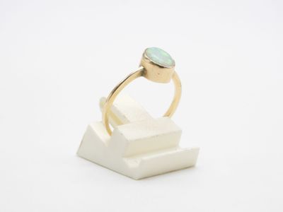 Gros plan sur une bague en or ornée d'une pierre verte