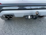 the rear end of a silver car with a black exhaust pipe