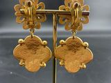 a close up of a pair of gold earrings on a stand