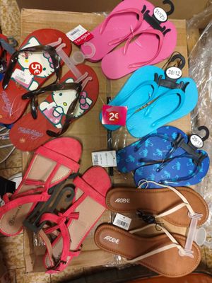 de nombreuses paires de tongs dans une boîte posée par terre
