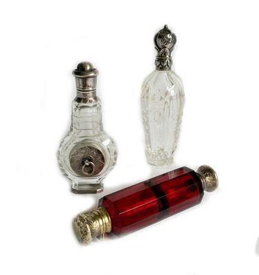three bottles and a clock on a white surface