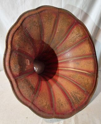 un vase rouge et marron posé sur une surface blanche