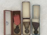 three medals are in a box on a white surface
