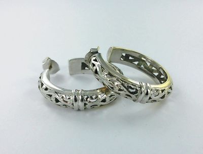 paire de bagues en argent ornées de motifs en filigrane sur un fond blanc