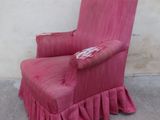 a pink chair with ruffles on it in front of a wall