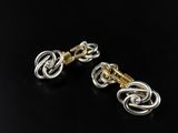 a pair of gold and silver earrings on a black background
