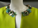 green jacket with multi colored buttons on a mannequin neck