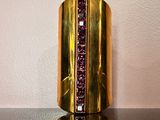 bracelet manchette violet et doré, orné de pierres violettes sur un fond noir