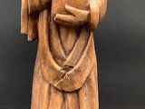 wooden statue of a monk holding a book and wearing a robe