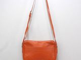 an orange purse hanging on a wall with a white wall behind it