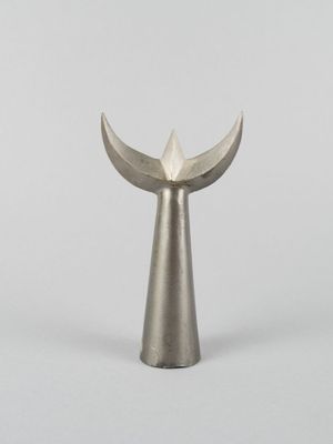 un vase en argent dont le couvercle a la forme d'un oiseau, posé sur un fond blanc