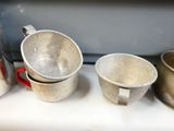 three pots and two cups on the counter