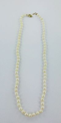 un collier de perles blanches avec un fermoir en or
