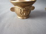 a small gold bowl with a lion head on it