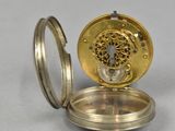 an antique pocket watch with a gold case on a white surface