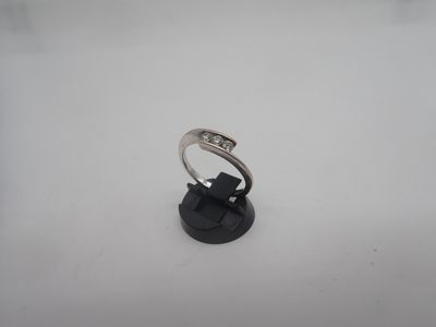 une bague en or blanc sertie de diamants, posée sur un socle noir