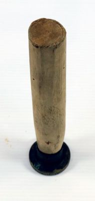 un petit poteau en bois avec une base noire sur une surface blanche