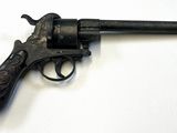 un vieux pistolet avec une poignée en bois sur une surface blanche