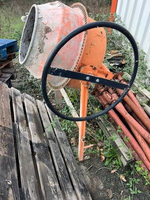 une bétonnière posée à côté d'un tas de bois