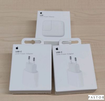 trois boîtes blanches contenant des chargeurs USB Apple posées sur une surface en bois