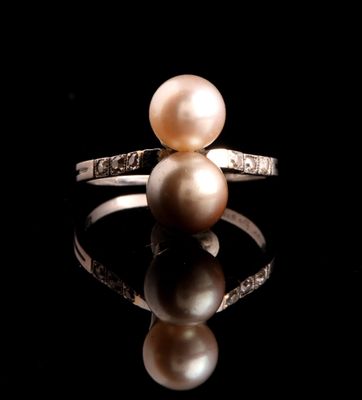 bague en perle et diamant posée sur une surface réfléchissante