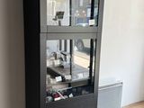 une armoire noire avec une porte vitrée, placée dans un coin de la pièce