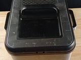 une photo représentant un récipient en plastique noir posé sur une table en bois