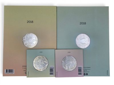 quatre livres de couleurs différentes, sur lesquels figurent des pièces de monnaie, posés sur une surface blanche