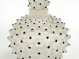 a white glass bottle with black dots on it