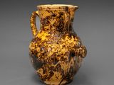 un vase marron et noir posé sur une surface grise