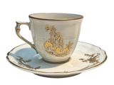 a cup and saucer with a gold design on it