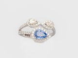 a close up of a diamond and blue sapphire ring on a white background