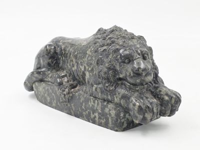 une statue représentant un lion couché sur un rocher