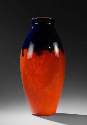 un vase orange et bleu posé sur une surface blanche