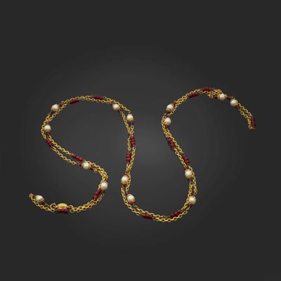 un collier en or avec des perles et une chaîne sur fond noir