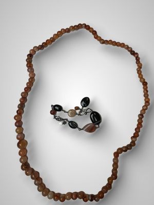 une image représentant un collier avec des perles et une bague sur un fond blanc