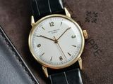 a gold watch with a white face on a black leather strap