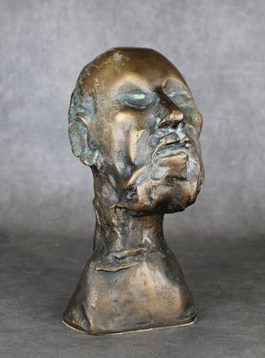 sculpture en bronze représentant la tête d'un homme sur fond gris